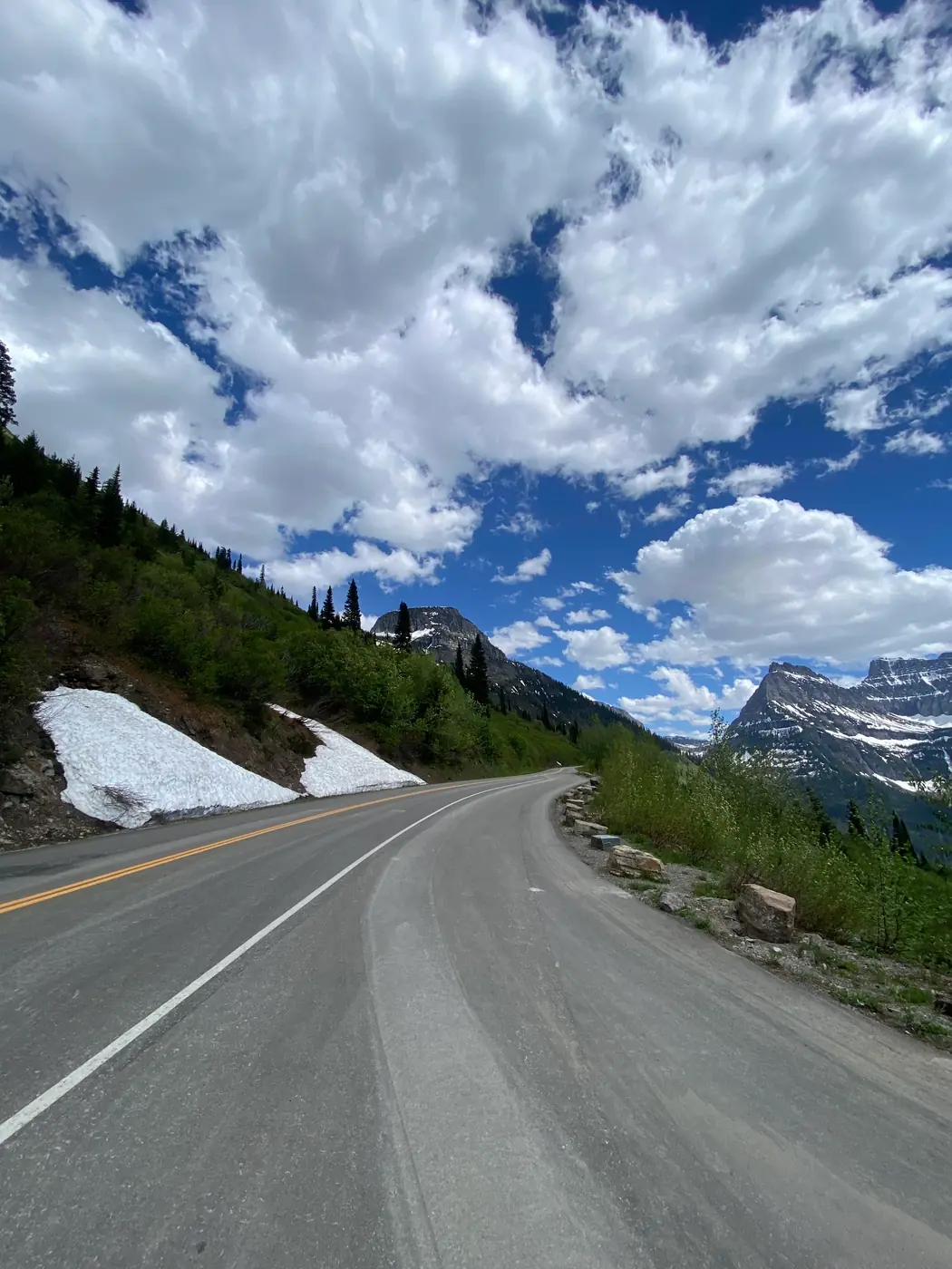 The empty Going-to-the-Sun Road curving below snow-streaked peaks in Glacier National Park