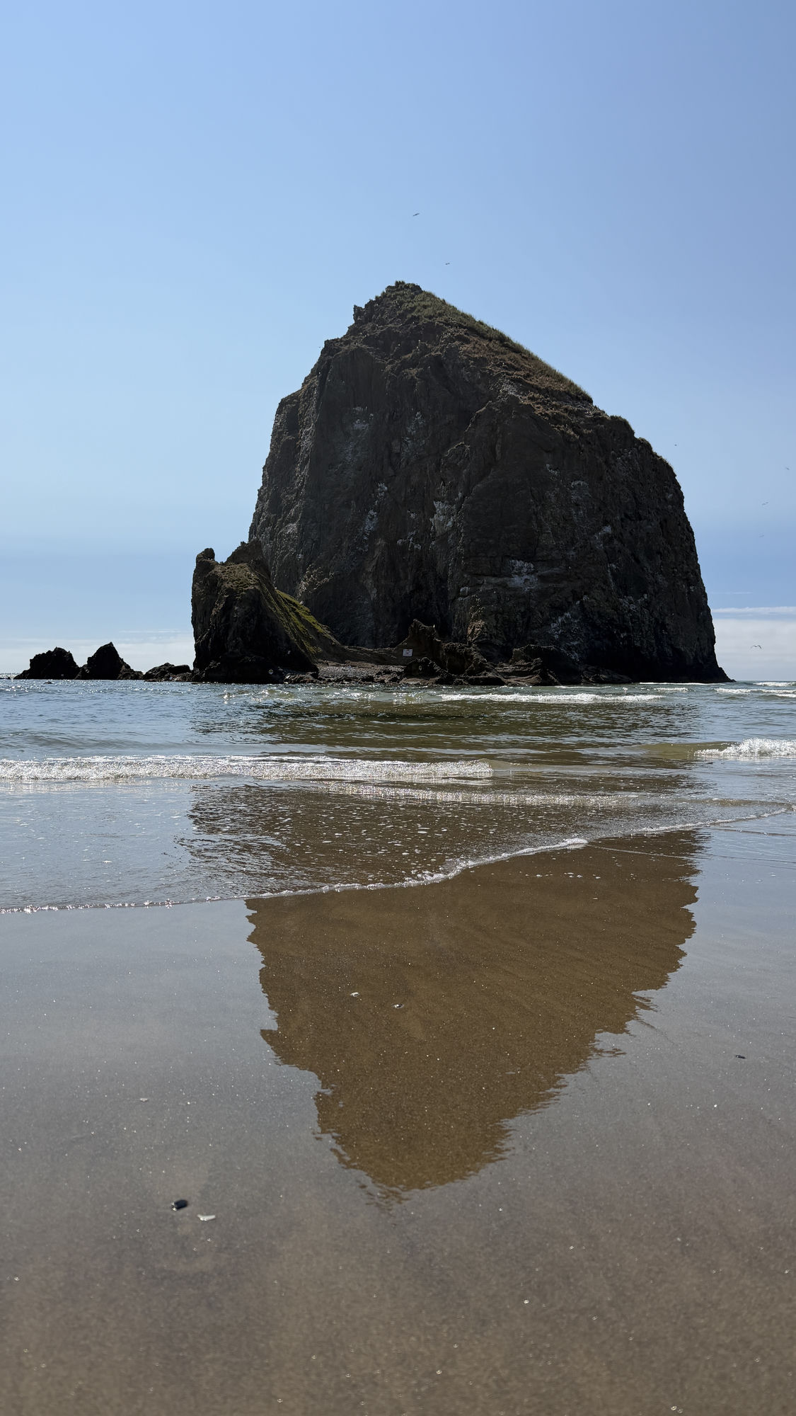 Haystack Rock reflected on the wet sand at Cannon Beach on the Oregon Coast